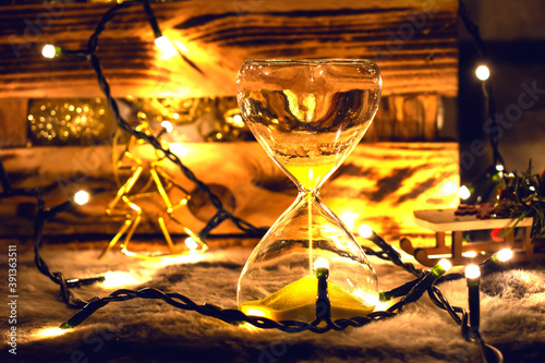 Hourglass on the background of a box with toys for the Christmas tree. For the moment, before Christmas © Max