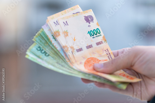 Bild auf Leinwand Hand giving Argentinian pesos - Argentinian Money