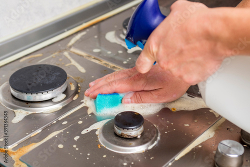 Man hand cleaning gas stove using sponge and detergents. Cleaning a gas stove with kitchen utensils, household concepts, or hygiene and cleaning