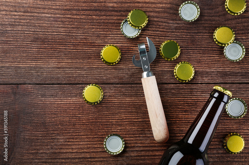 Bottle caps with bottle and opener on brown wooden table