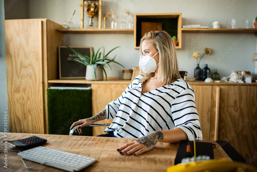 Bonita chica rubia en oficina con mascarilla. Chica rubia mirando pantalla ordenador con mascarilla por la situación del COVID-19. Mujer protegida por la pandemia. Bonita chica rubia en oficina con mascarilla. Chica rubia mirando pantalla ordenador con mascarilla por la situación del COVID-19. Mujer protegida por la pandemia.