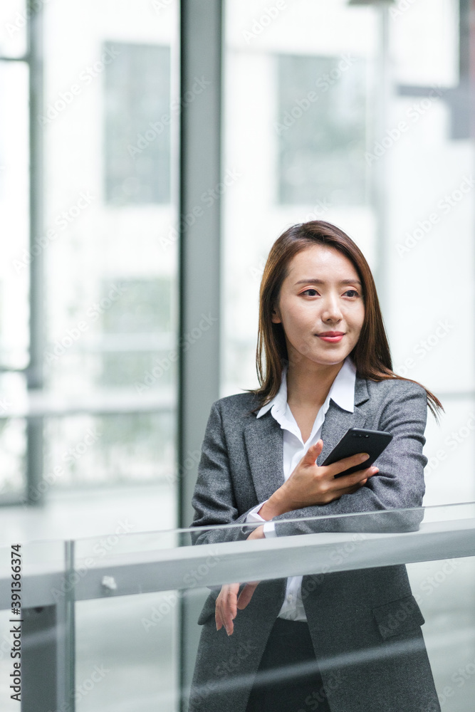 Businesswoman Using Cell Phone In Office Buildings Businesswoman Using Cell Phone In Office Buildings