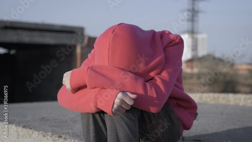 Adolescence feels unhappy. A view of an unhappy hopeless teen sits alone in the field. photo