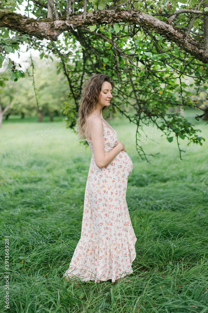 Adult pregnant lady walking through garden in summer Adult pregnant lady walking through garden in summer