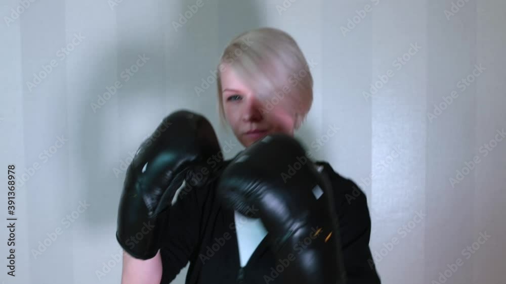 Boxing with your hands. Portrait of a woman doing a workout at home with boxing gloves. Raising the tone of the muscles of the arms and body. Burning fat in self-isolation. Boxing with your hands. Portrait of a woman doing a workout at home with boxing gloves. Raising the tone of the muscles of the arms and body. Burning fat in self-isolation.