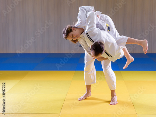 Adult male judoka throwing young female judo girl with hip throw