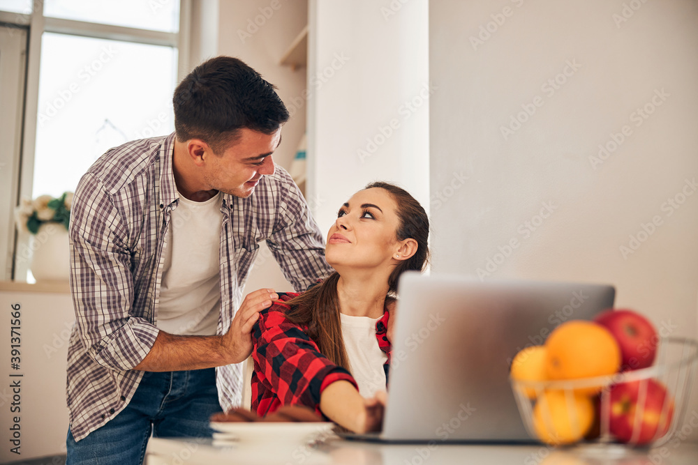 Female teleworker looking at her handsome male spouse Female teleworker looking at her handsome male spouse