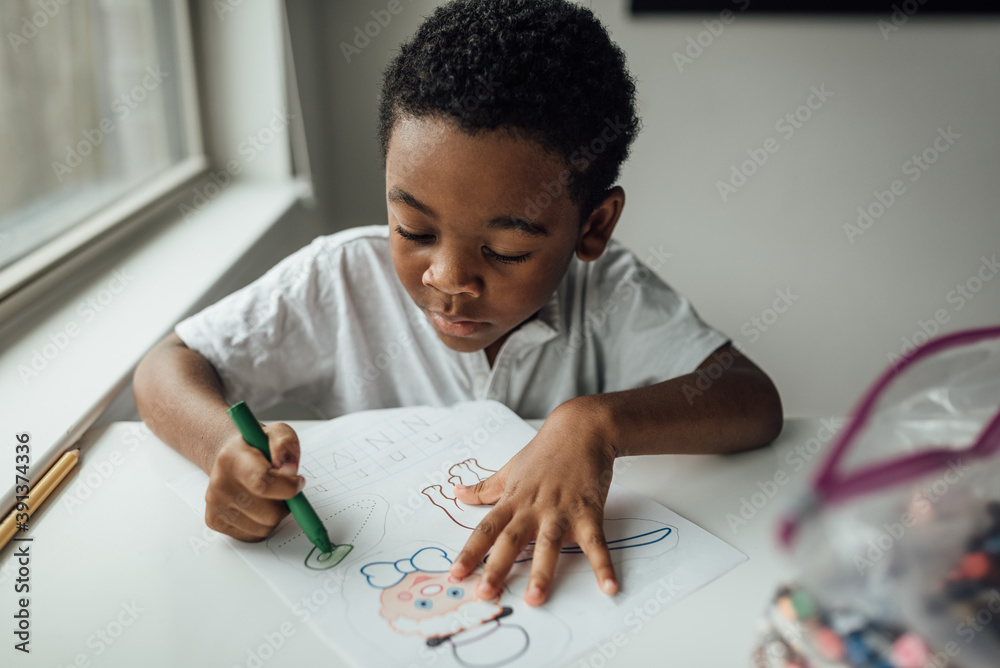boy coloring and writing at the kitchen table boy coloring and writing at the kitchen table
