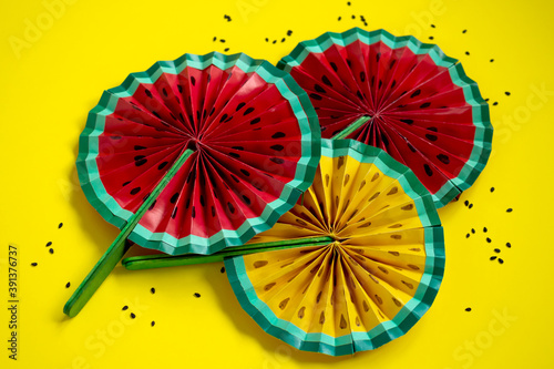 Paper fruit origami watermelon fan decoration close up on bright yellow background. Tropics summer