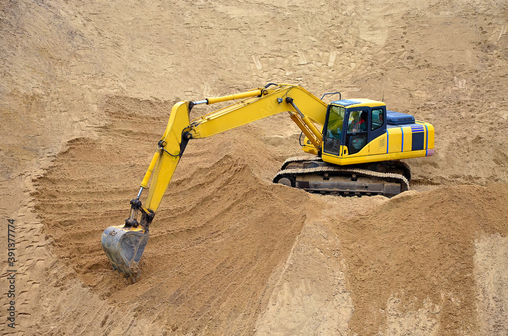 Yellow excavator levels its bucket of sand, earth, clay. Construction of a sand embankment Yellow excavator levels its bucket of sand, earth, clay. Construction of a sand embankment