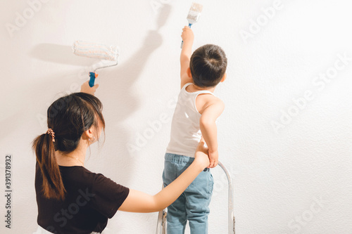 Mother and son painting the wall together. Mom and child fun times photo