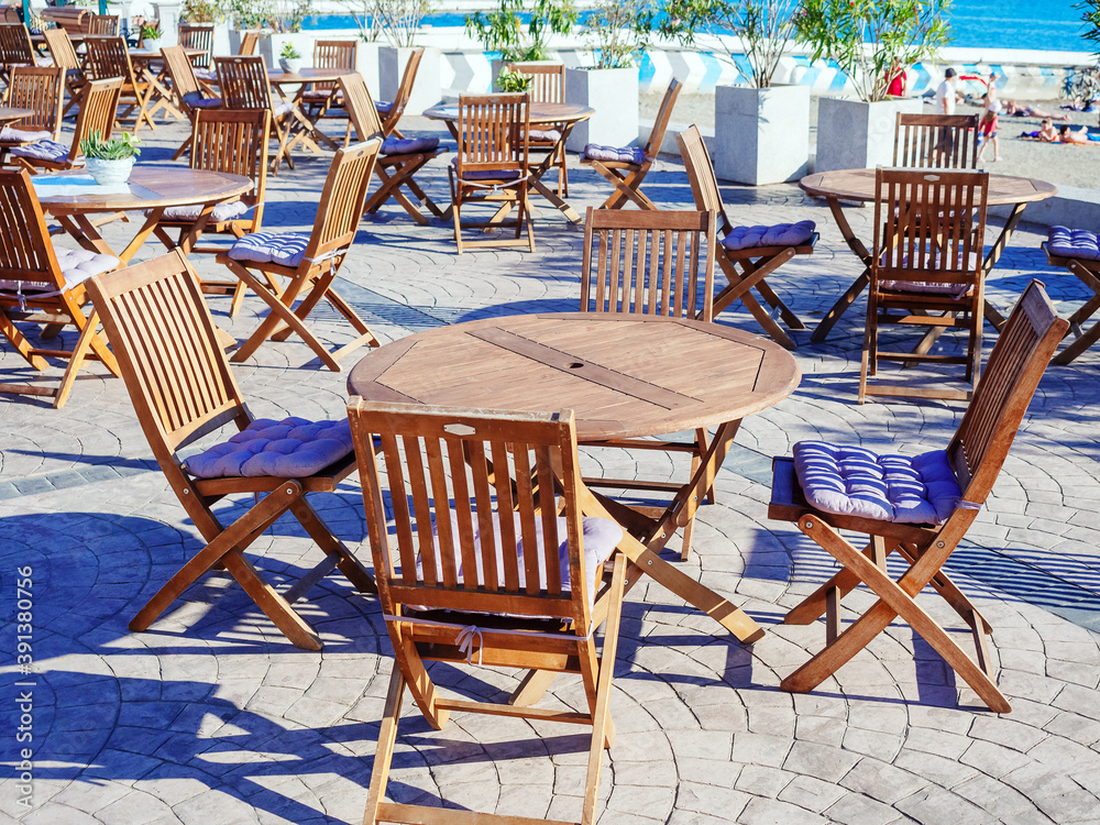 Street seaside cafe with round wooden tables and folding chairs