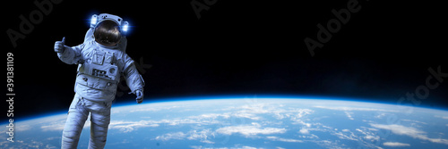 astronaut during a spacewalk in orbit of planet Earth, background banner format
