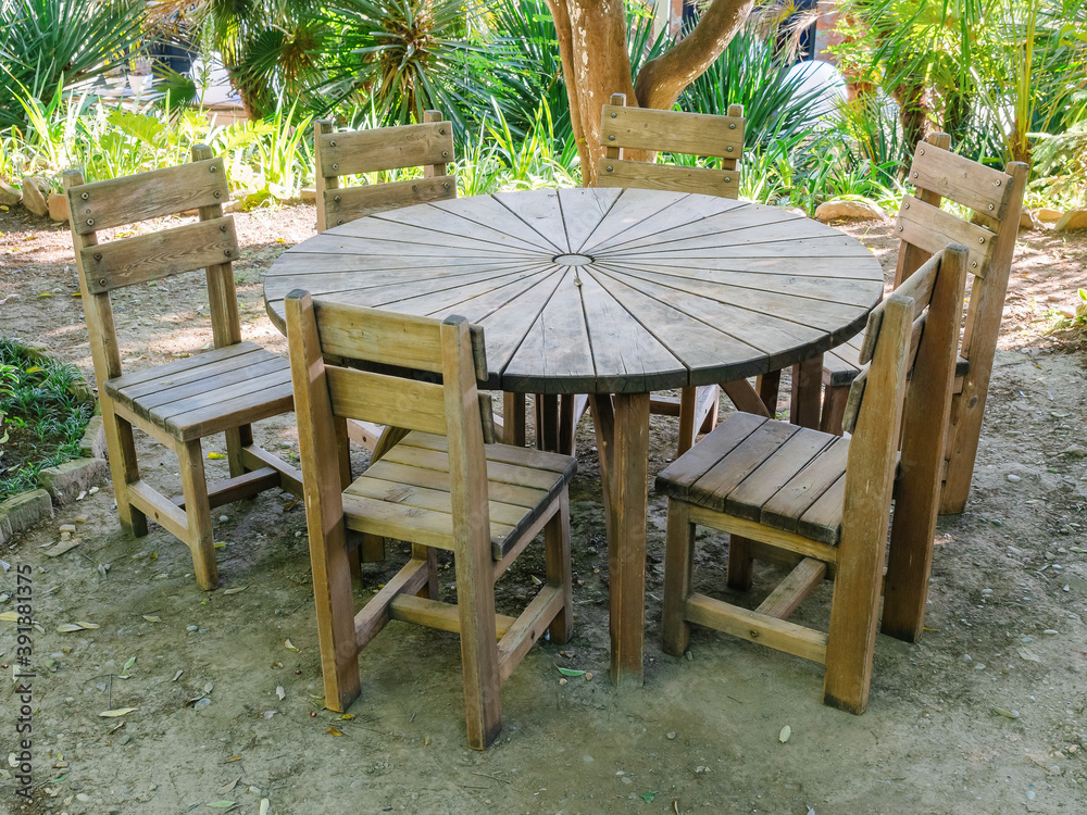 Round wooden table and chairs of a street cafe stand on the ground