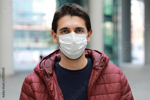 Portrait of worried man in modern city street wearing protective face mask