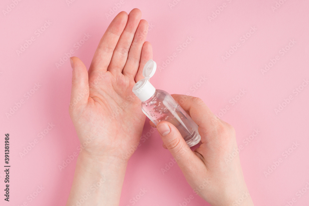 Top above overhead close up pov first person view photo of female applying gel sanitizer to her hands isolated on pink pastel background with copyspace Top above overhead close up pov first person view photo of female applying gel sanitizer to her hands isolated on pink pastel background with copyspace