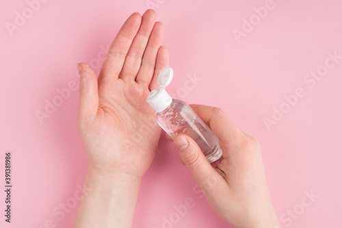 Top above overhead close up pov first person view photo of female applying gel sanitizer to her hands isolated on pink pastel background with copyspace
