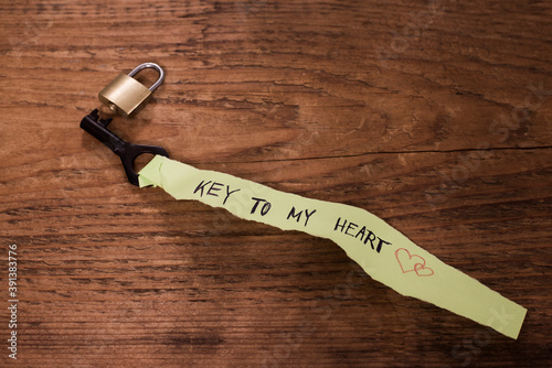 vintage black brass key on turquoise with golden metaL lock lie of old retro vintage style adged wooden texture background with funny concept of phrase key to my heart Empty copy space for inscription photo