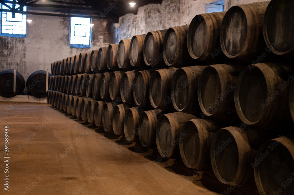 Old porto lodge with rows of oak wooden casks for slow aging of fortified ruby or tawny porto wine in Vila Nova de Gaia, Portugal Old porto lodge with rows of oak wooden casks for slow aging of fortified ruby or tawny porto wine in Vila Nova de Gaia, Portugal