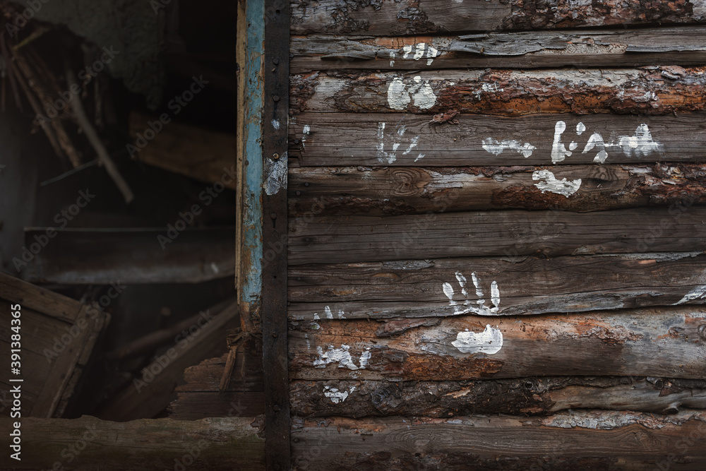White prints of human palms on the wooden beams of the wall of a broken abandoned cottage in which you can see the mess. White prints of human palms on the wooden beams of the wall of a broken abandoned cottage in which you can see the mess.