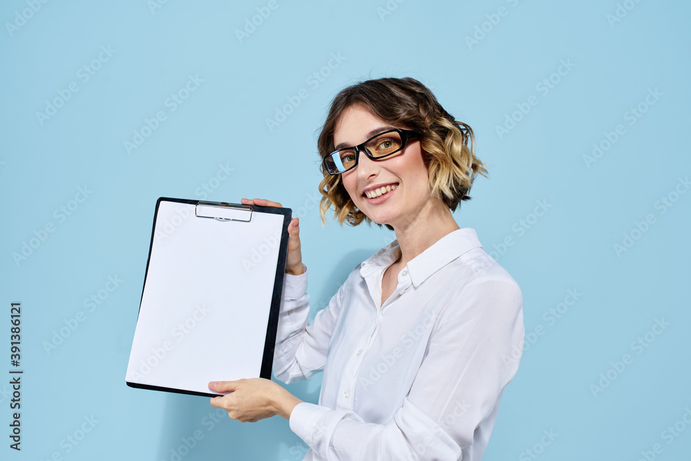 Business woman with documents in a folder on a blue background and in a light shirt glasses on her face Business woman with documents in a folder on a blue background and in a light shirt glasses on her face