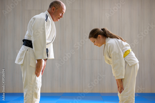 Fotografie, Obraz Young female judo girl showing respect to old judo teacher