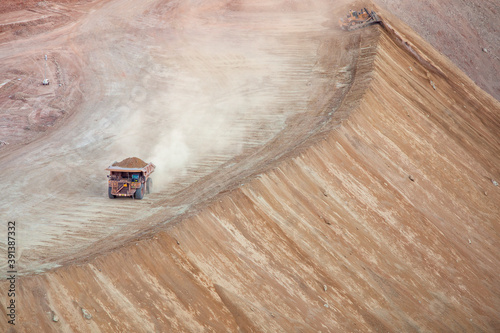 Large dump truck stirs up dust hauling dirt in strip mining operation photo