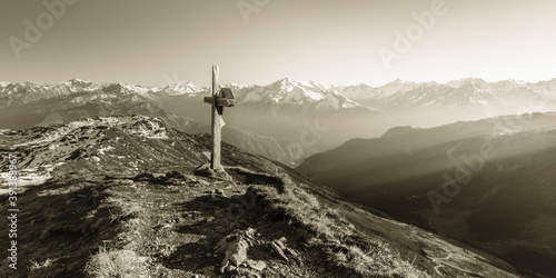 Schilderij op canvas Panorama einer Berglandschaft mit Gipfelkreuz in sepia