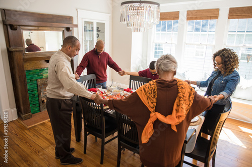 Black multigenerational family praying and blessing the food for Thanksgiving holiday meal photo