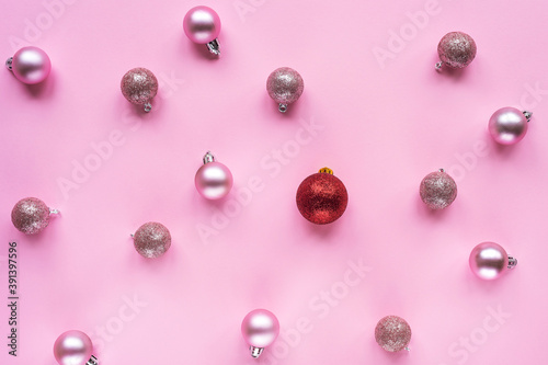 One red christmas ball and many pink ones on the table. Christmas or New Year concept. Different, non-standard. Top view