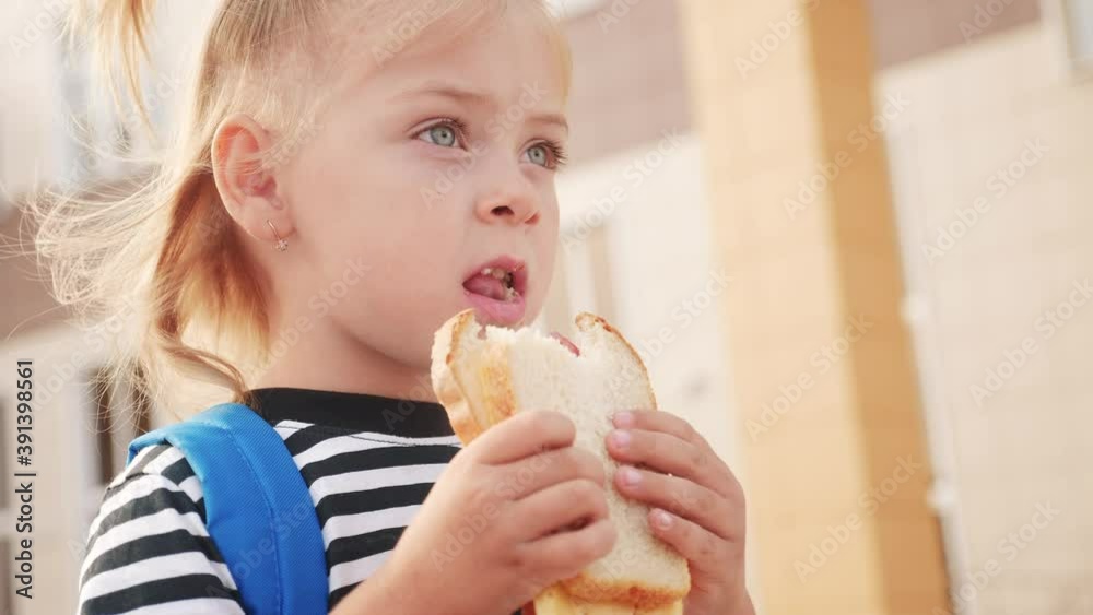 schoolgirl eating a sandwich during recess in school. kids education concept. little girl kid lifestyle schoolgirl with a backpack eating a sandwich. kid child is having lunch at school schoolgirl eating a sandwich during recess in school. kids education concept. little girl kid lifestyle schoolgirl with a backpack eating a sandwich. kid child is having lunch at school