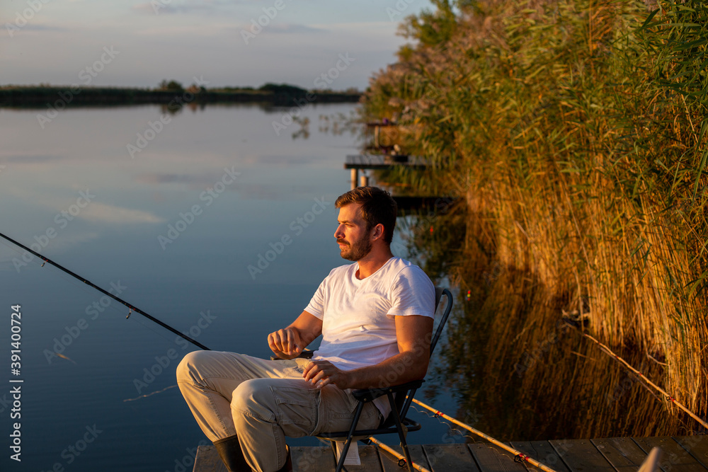 Handsome man fishing on a lake at the sunset. Handsome man fishing on a lake at the sunset.
