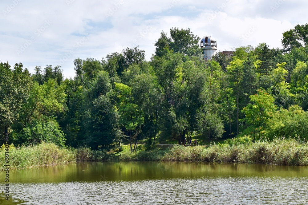 Lake  in the park with an abandoned observatory towering above the trees, Moldova, July 2018