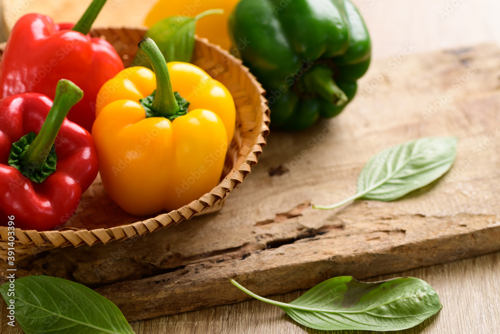 Fresh yellow, red and green bell peppers in a bamboo basket on wooden background, Organic vegetables Fresh yellow, red and green bell peppers in a bamboo basket on wooden background, Organic vegetables