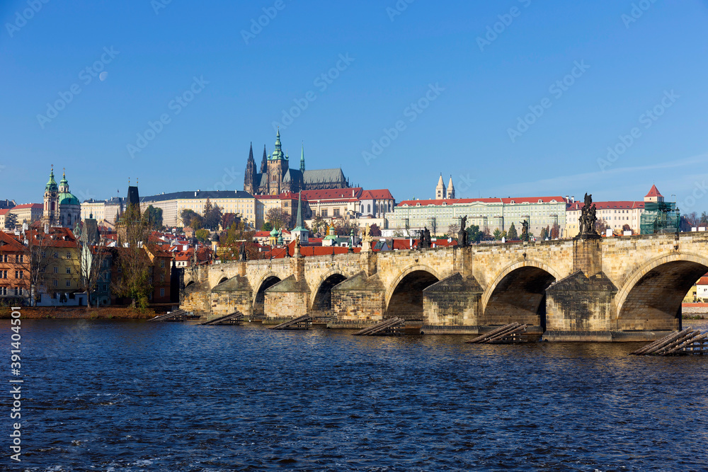 Autumn colorful Prague Lesser Town with gothic Castle and Charles Bridge above River Vltava in the sunny Day, Czech Republic