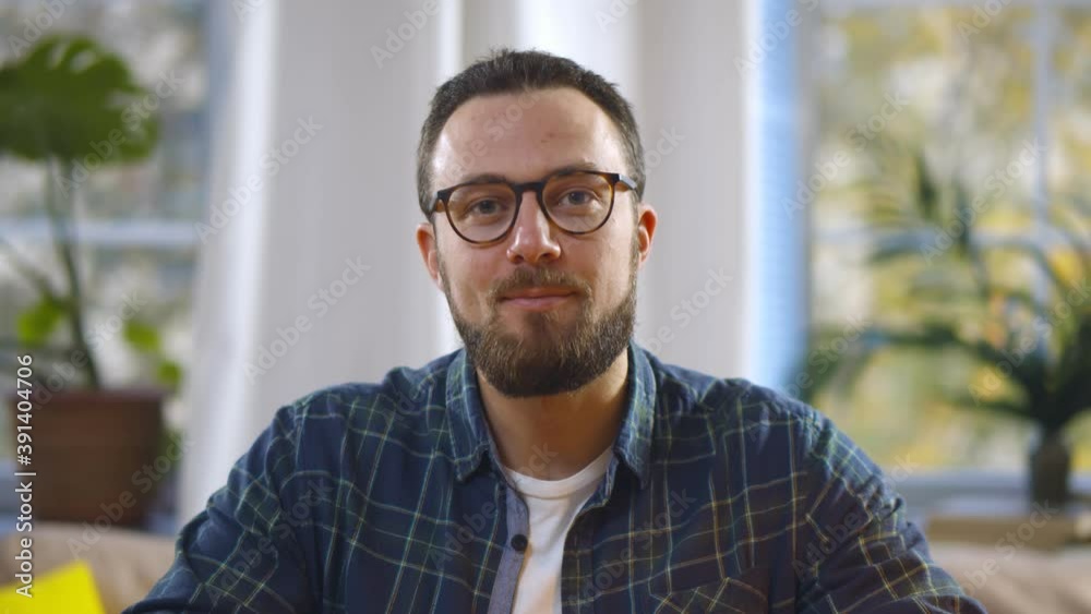 Portrait of handsome bearded man looking at speaking at camera having video call from home