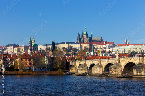 Autumn colorful Prague Lesser Town with gothic Castle and Charles Bridge above River Vltava in the sunny Day, Czech Republic