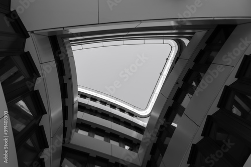 Obraz na plátně Black and white color and tone, low angle diminished perspective view inner atrium surrounded with curvature facade and wall with big hole through the sky