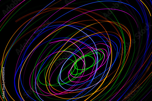 Multi color light painting photography  swirl and curve of blue  green and red light against a black background.