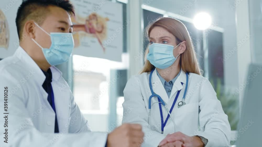 Multi-ethnic couple of doctor and nurse wearing protective masks discussing disease and treatmet diagnosis medicine at hospital healthcare office. Multi-ethnic couple of doctor and nurse wearing protective masks discussing disease and treatmet diagnosis medicine at hospital healthcare office.