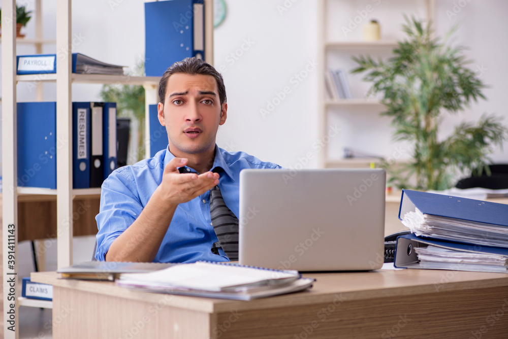 Young businessman employee unhappy with excessive work in the o Young businessman employee unhappy with excessive work in the o