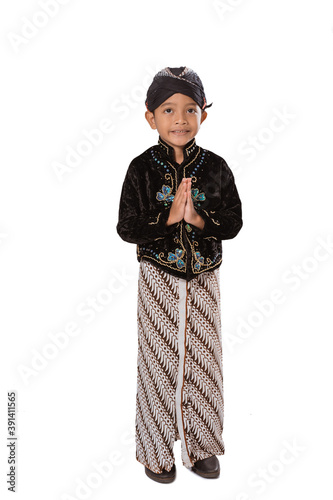 Portrait of a child in Javanese traditional clothes. Pose greetings isolated on white background photo