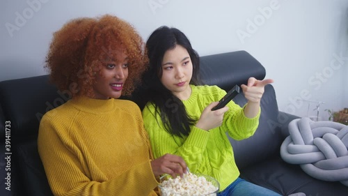 Multiracial friendship. Afican american black and asian woman eating popcorns and watching movies. High quality 4k footage photo