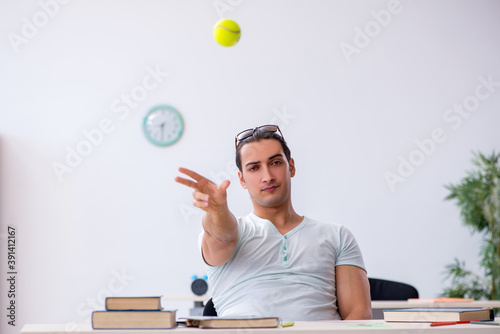 Young male student throwing tennis ball during exam preparation