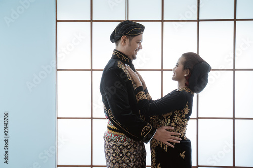 Portrait happy men and women wearing javanese traditional clothes. Couple concept photo standing by the window