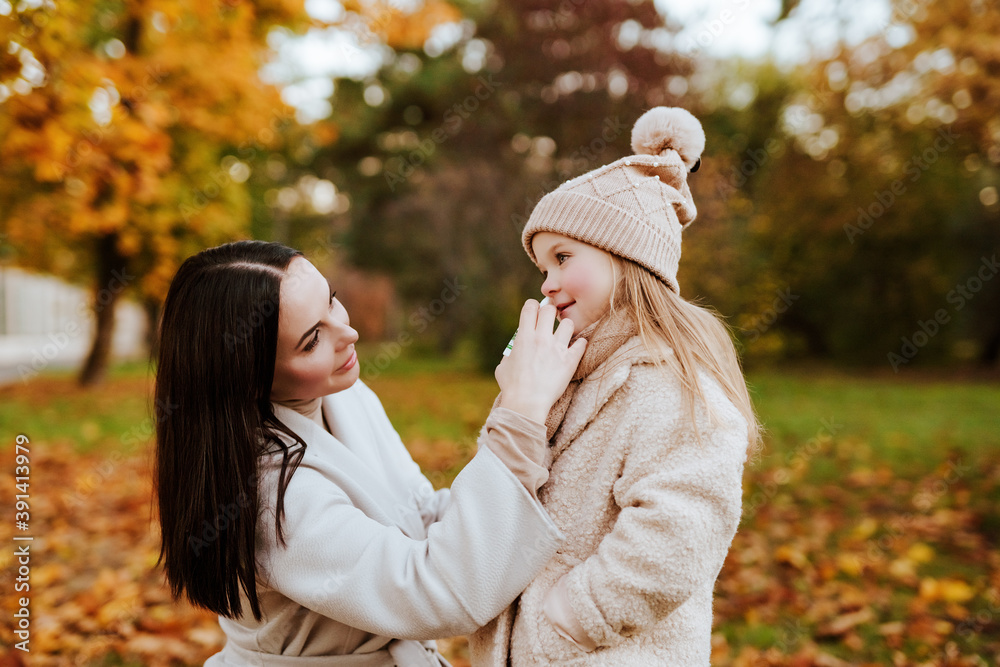 mom buries spray in nose of little daughter in hat and scarf in autumn Park mom buries spray in nose of little daughter in hat and scarf in autumn Park
