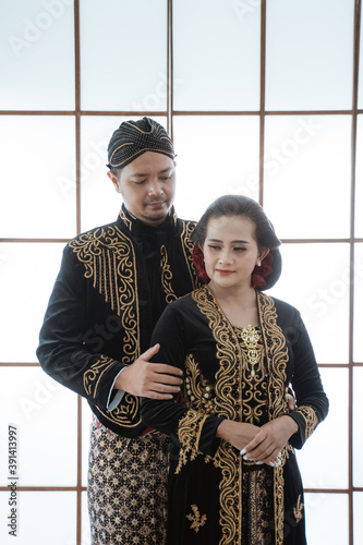 Portrait happy men and women wearing javanese traditional clothes. Couple concept photo standing by the window photo