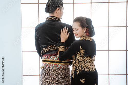 Portrait happy men and women wearing javanese traditional clothes. Couple concept photo standing by the window photo