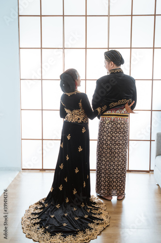 Portrait happy men and women wearing javanese traditional clothes. Couple concept photo standing by the window photo