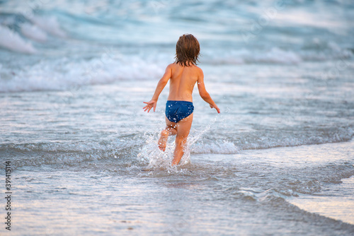 Vacation with children. Happy child running in the sea. Kid boy having fun on the beach. Summer kids.